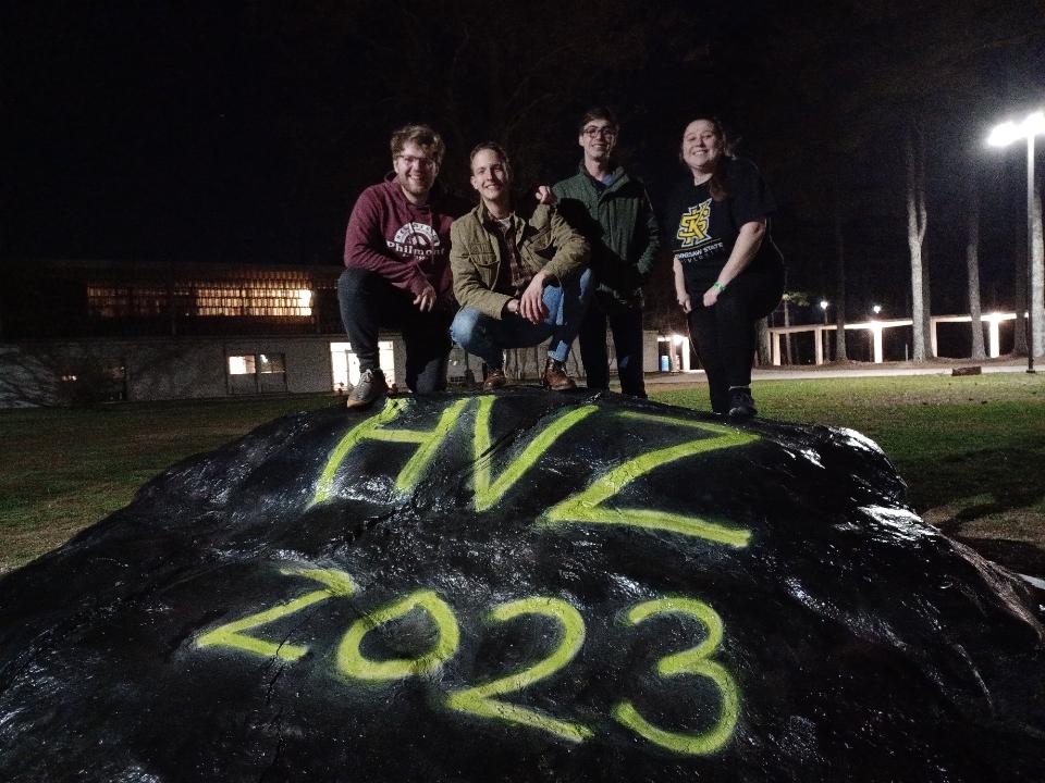 Students posing around a painted campus rock for HVZ